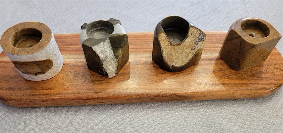 Carved soap stone candle holders sitting on a wooden board.