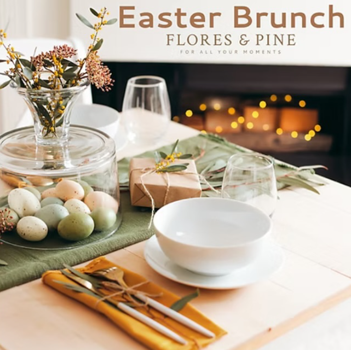A table setting with a fire behind. The colours are mostly soft pastel, and there is a open bottom glass vase with a flower arrangement in it, and eggs underneath.