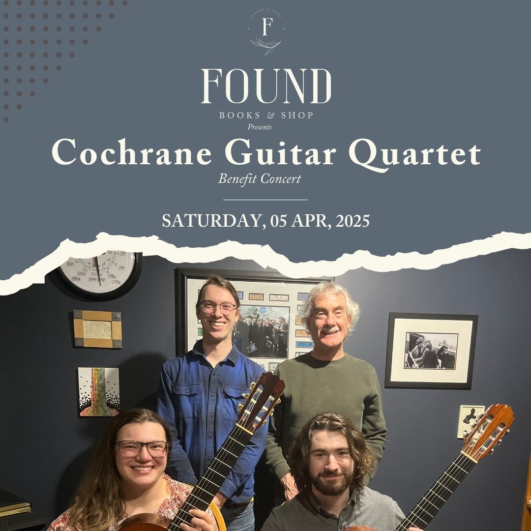 Four musicians stand in a group. The two in front are holding guitars.